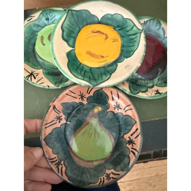 A vibrant set of four hand-painted Mexican pottery plates featuring bold fruit motifs in rich, saturated color. Each plate...