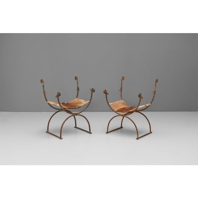 Pair of steel framed curule chairs with hide seats and worn original paint finish. Circa 1930.