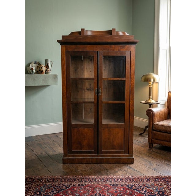 This piece is a classic Biedermeier style double-door bookcase vitrine, characterized by the clean lines, understated...