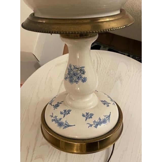 This vintage lamp is a white porcelain and brass lamp with a floral pattern. It has a ginger jar shape and decorative...