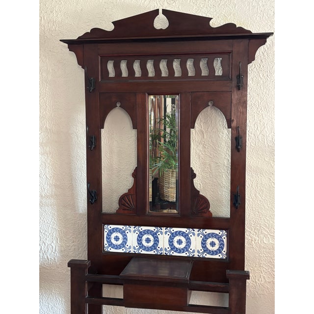 Antique 1800s English Victorian carved wood hall tree with beveled mirror. Features blue and white tile accents, six hooks...