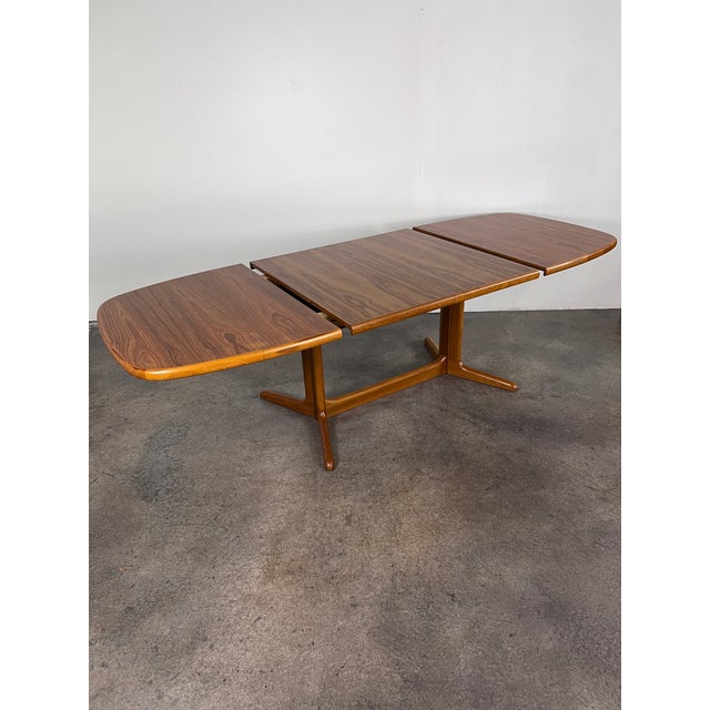 Beautifully grained mid century Danish modern teak expanding dining table with two hide-a-way leafs. (Refinished). The...