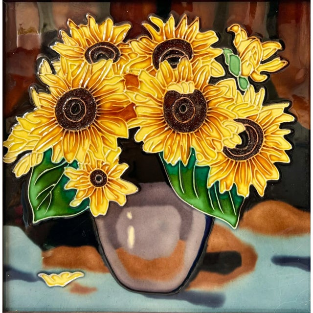 Captivating, large ceramic tile depicting a vase full of sunflowers with raised borders and a dark wood frame. Made in the...