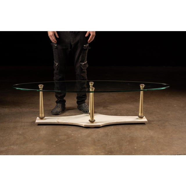 Vintage glass coffee table with a marble base. This unique piece features a wide, tempered glass top held in place on top...