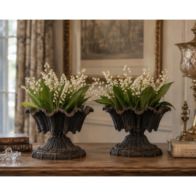 A handsome pair of antique cast iron garden urns of classical form, each with a deeply fluted, oval bowl and dramatically...
