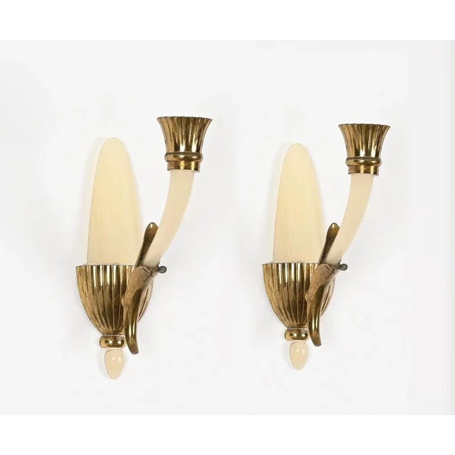 Magnificent pair of wall lamps in a gorgeous ivory murano artglass and brass. These charming sconces were designed by...