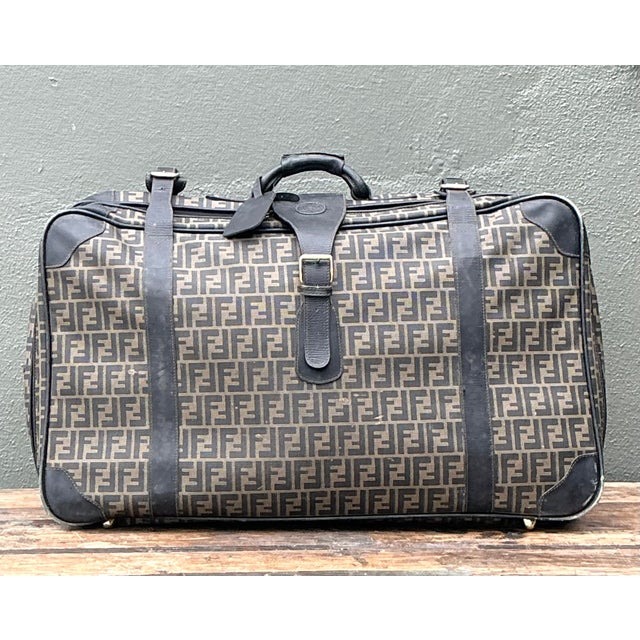 Embark on your next journey with the unmistakable elegance of Fendi. This vintage suitcase features the iconic "Zucca"...
