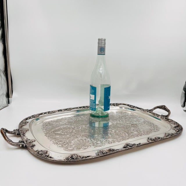 Vintage silverplate tray featuring raised grape-and-vine motifs along the border and a central etched design with...