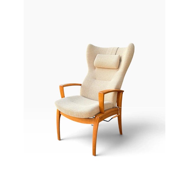 OVERVIEW A tall Danish modern wingback recliner, attributed to Farstrup of Denmark, upholstered in a creamy bouclé....