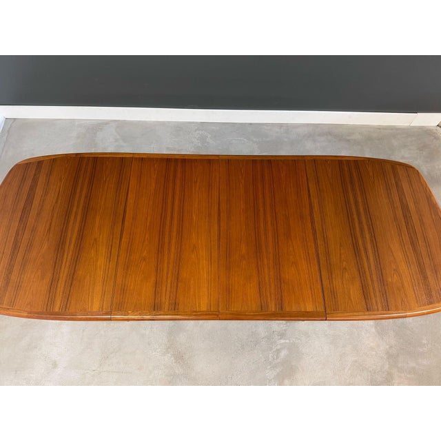 A mid century modern teak dining table with two 20” leaves which fully extend the table to 98.75”. Professionally...