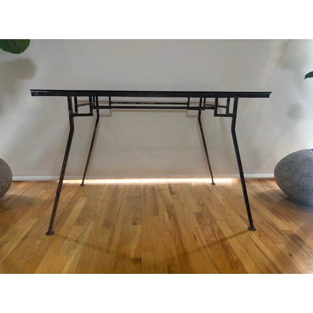 Sculptural vintage iron and glass table featuring an architectural geometric frame, slender tapered legs, and a clear...