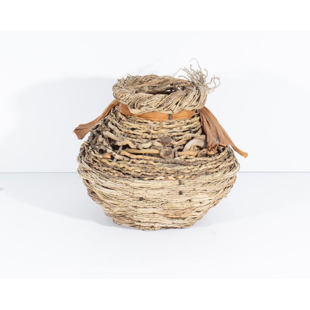 A handwoven artisan basket by Samuel Yao. This basket is woven from various material from palm trees. An artist's card is...