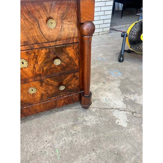 A handsome French 19th century Empire commode featuring a richly figured walnut veneer, elegant black marble top, and...