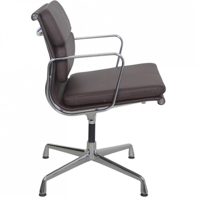 Charles Eames EA208 softpad chair upholstered in Nevada coffee anilin leather, and with a chrome frame and armrests. The...