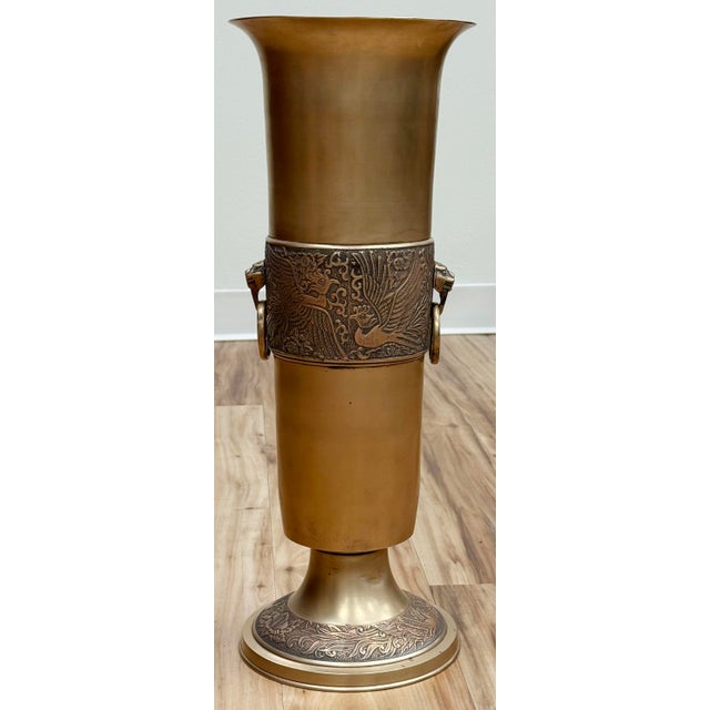 Vintage brass umbrella or cane stand featuring a flared top, weighted pedestal base and ornate bird motif banded middle....