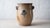 Ovoid salt-glazed stoneware jar with a footed base, tooled collar, and open loop handles, the handle terminals brushed in...