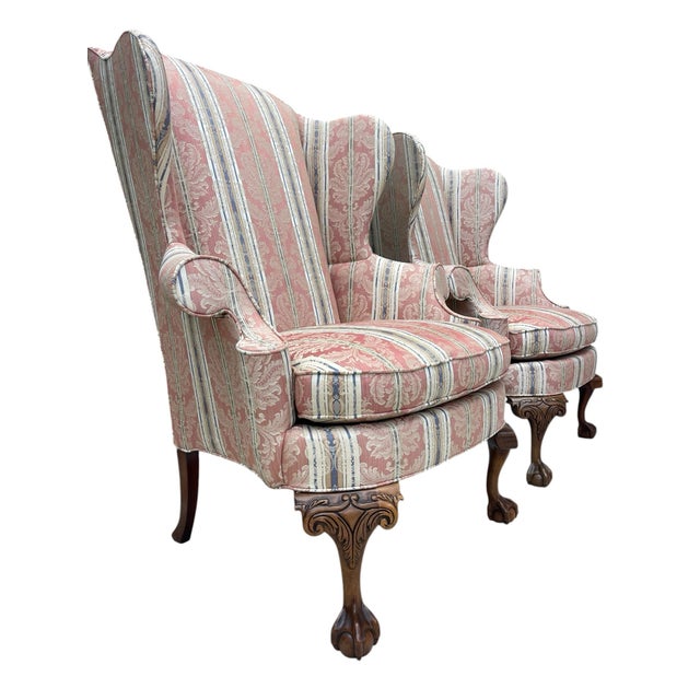 A refined pair of Queen Anne style wingback lounge chairs by Southwood, dated 1993, distinguished by elegantly carved...