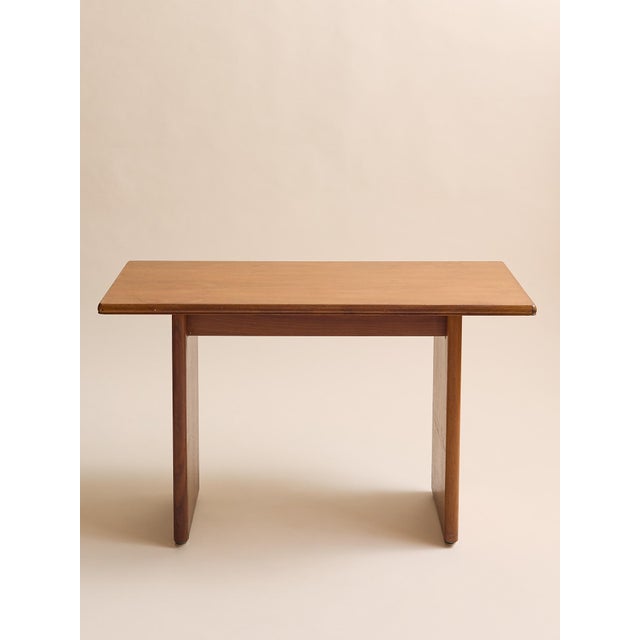 A beautifully minimal mid-century modern console table in warm teak, defined by its clean architectural lines and softly...