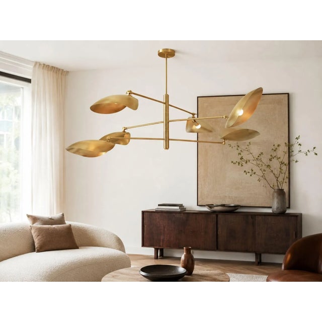 A handcrafted solid brass mobile chandelier featuring six adjustable sculptural shades arranged along a balanced...