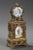 Small table clock in gilt brass richly decorated with openwork scrollwork, acanthus leaves, flowers, and masks in...
