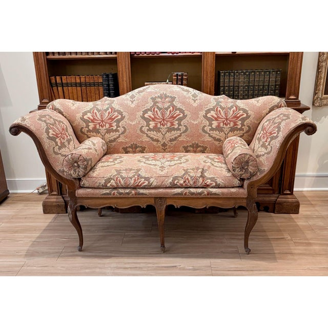 A very sculptural Italian walnut settee with a shaped, arched back and graceful outswept arms that end in carved scrolls....