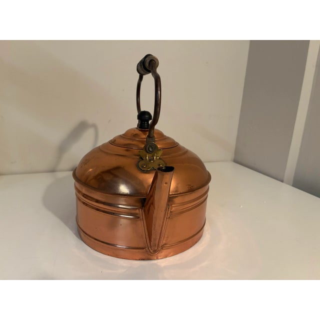 Offering an Antique Large Copper Tea Kettle w/ a Swinging Turned Wood Handle. The kettle measures approximately 9" in...