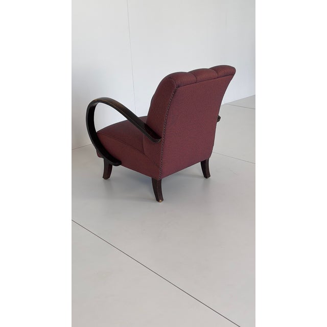Comfortable club chair with curved armrests made of lacquered wood. The understated design stylishly complements a modern...