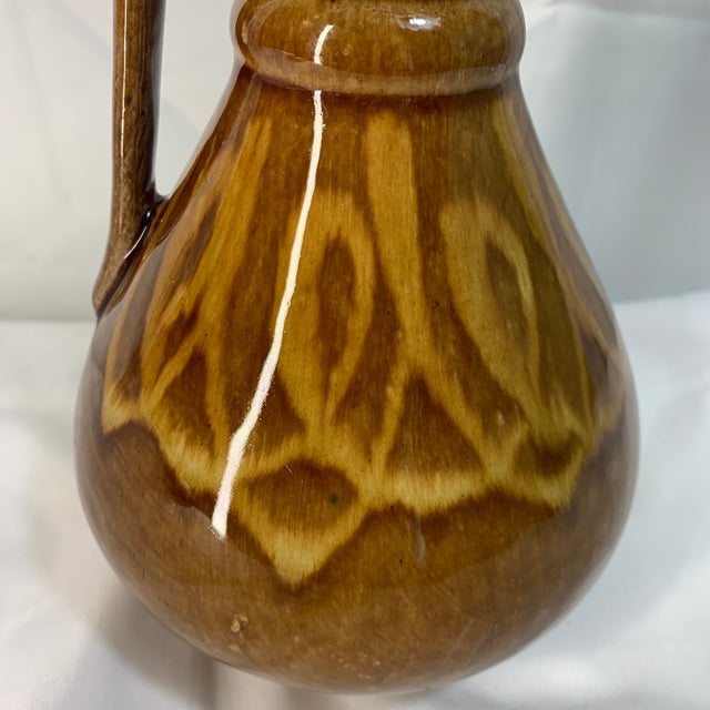 This is a vintage mid-century ceramic pitcher from Poland featuring a glossy chocolate-and-caramel brown drip glaze and a...