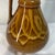 This is a vintage mid-century ceramic pitcher from Poland featuring a glossy chocolate-and-caramel brown drip glaze and a...