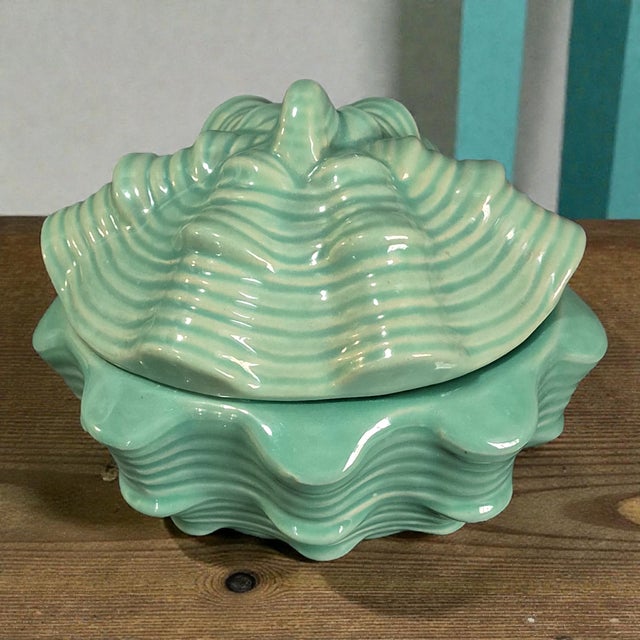 This Ceramic Celadon Color Coastal Seashell Shaped Covered Trinket Box is a charming and stylish decorative collectible...