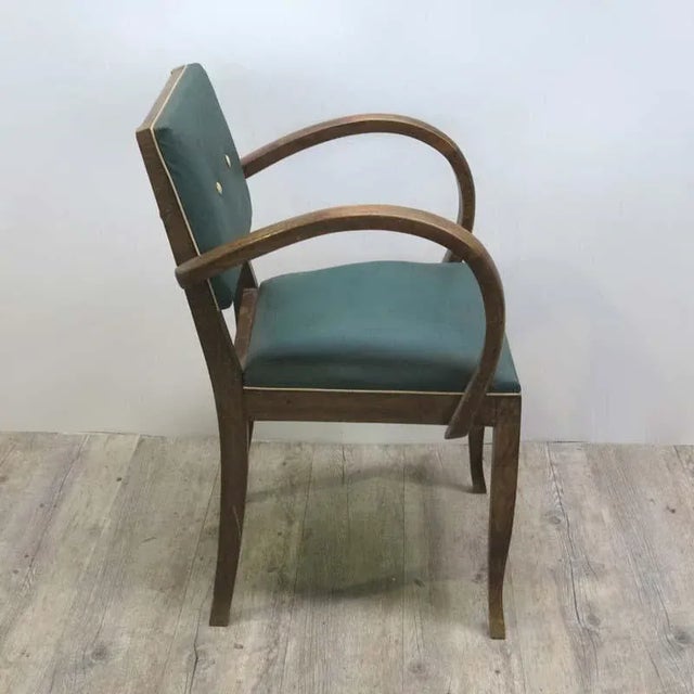 This Art Deco chair was produced in the period 1930 - 1935. It has a wooden frame and is upholstered in dark green Skai...