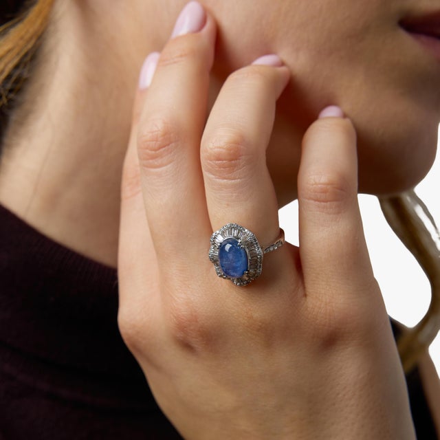 A captivating vintage ballerina ring centered around a mesmerizing 5.00 carat star sapphire, displaying a soft, luminous...