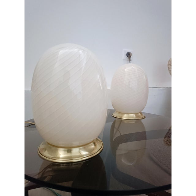 Magnificent pair of Egg table lamps. Italy, 1970s. Brass base. It features a large, egg-shaped tulip shade. Murano glass,...