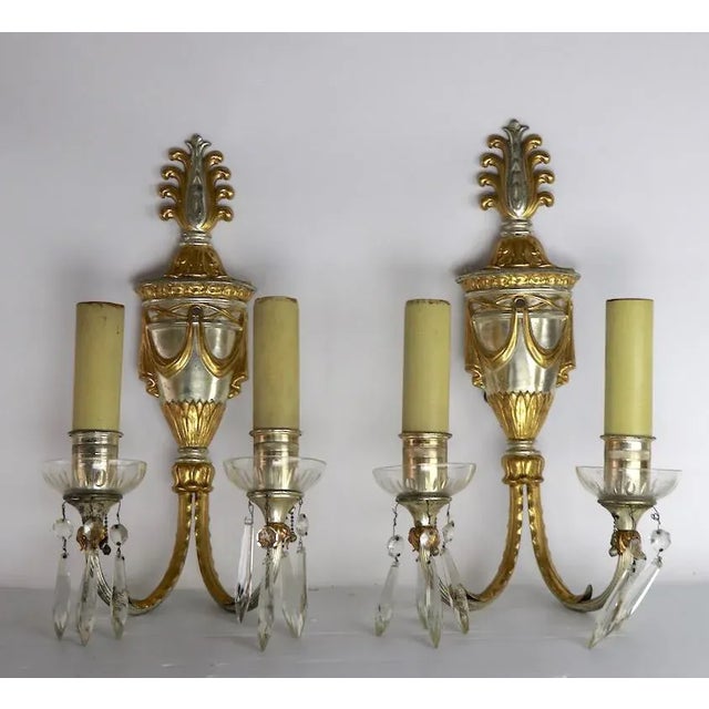 Fabulous and elegant pair of Classical Style sconces, each having two arms, a silver plate ground with brass color...
