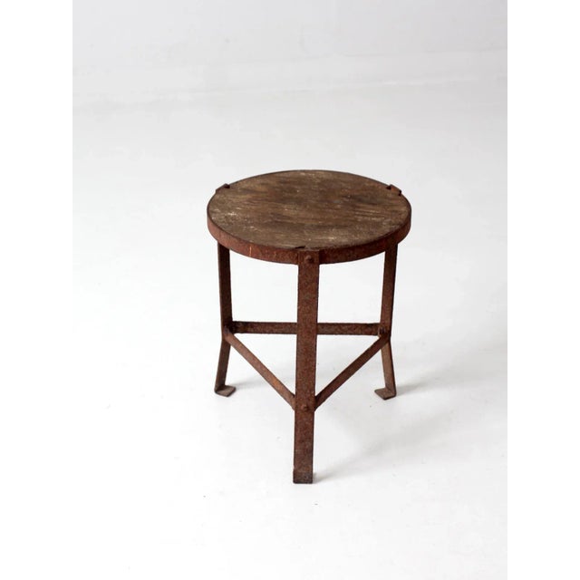 This is a vintage industrial stool. The three legged stool has a round wooden seat, and aged red barn paint colors the...