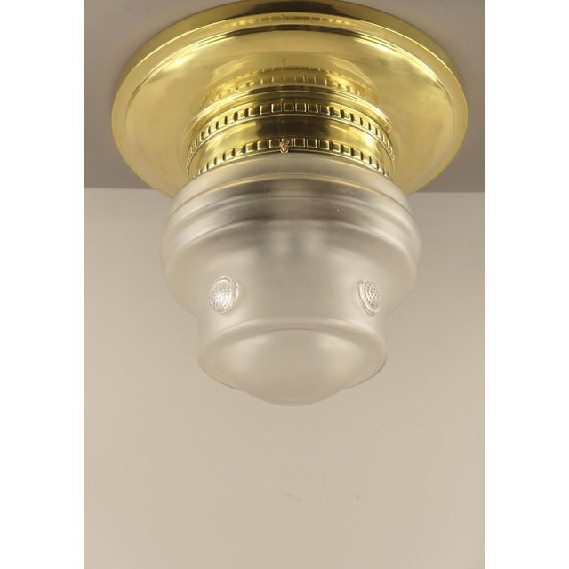 Massiv brass ceiling light with its original glass. Polished surface. The lamp gives a cosy, non-dazzling light. Up to...