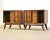 A pair of mid century modern walnut nightstands with sculpted x pulls and sliding doors. 26” wide. 17” deep. 24.75” tall.