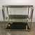 Large trolley / rolling table in gold metal with three shelves of smoked glass platforms. 4 casters. Vintage Italian...