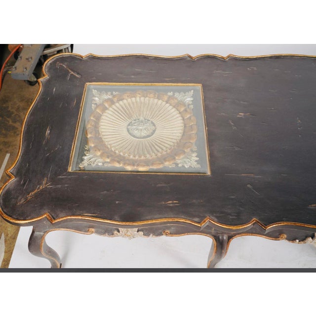 A dramatic 66-inch statement table combining French-inspired curves, distressed black paint and jewel-like gilt and...