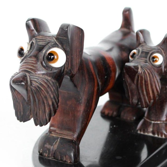 Art deco dogs in macassar ebony on a marble vide poche. Two macassar ebony dogs with glass google eyes. Art deco carved...