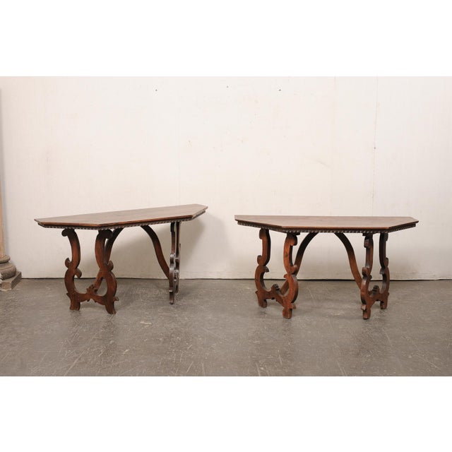 An Italian pair of carved wood demi console table from the 19th century. These antique tables from Italy each feature a...