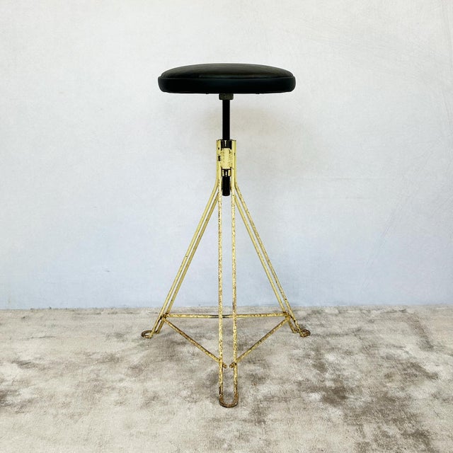 Wire-frame adjustable stool with tripod base in original cream paint finish and adjustable height mechanism operated via...