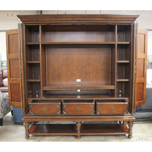 The piece shows a rich mahogany finish with factory distressing that highlights its carved panels and traditional...
