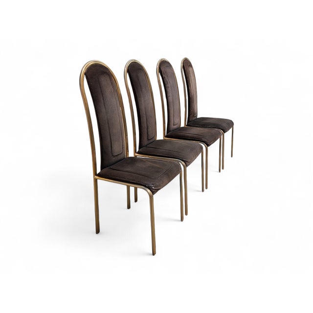This set of four vintage chairs stands out for its refined and dramatic design, featuring a slender gold-tone metal frame...