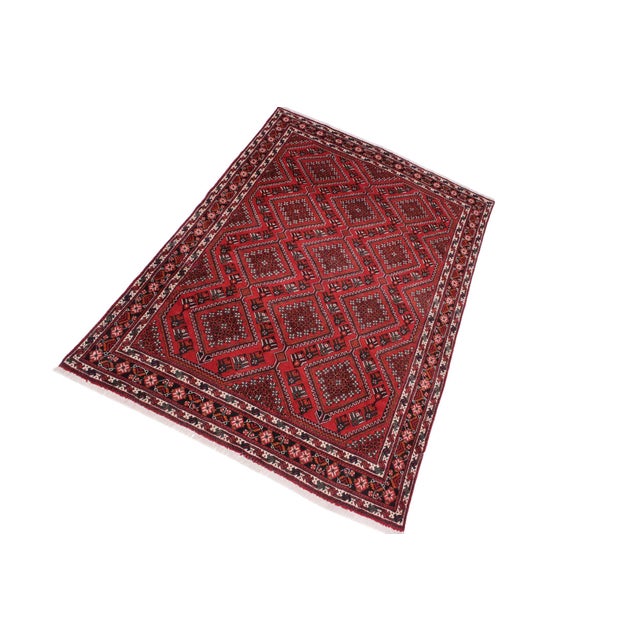 This beautiful antique hand-knotted wool rug features a rich red field with repeating geometric medallion motifs arranged...