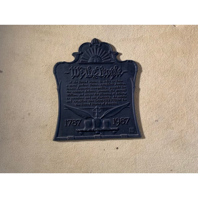 A commemorative cast iron fireback inscribed "We the People”, (the preamble to the U.S. Constitution) with a radiant sun...