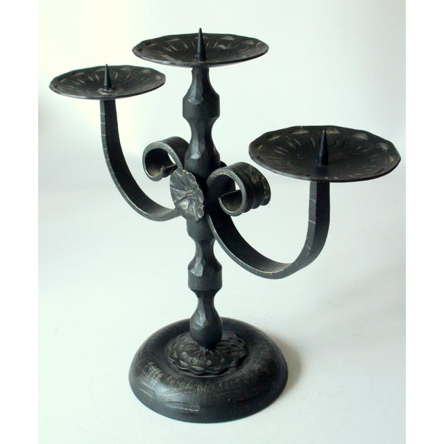 This three-armed handmade candle holder made of heavy wrought iron dates from the 1950s and bears the characteristic...