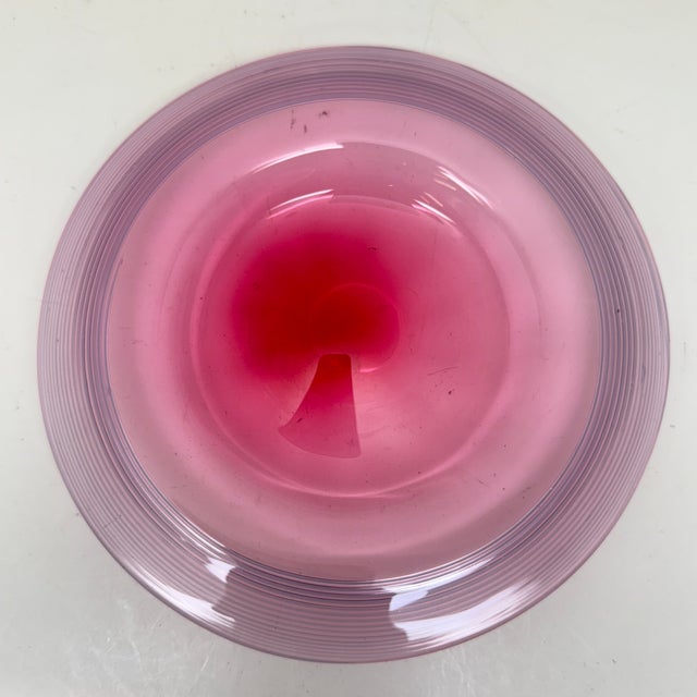 A hand-blown two-piece finger bowl set comprising a small footed/pontiled bowl and a matching circular underplate, both in...