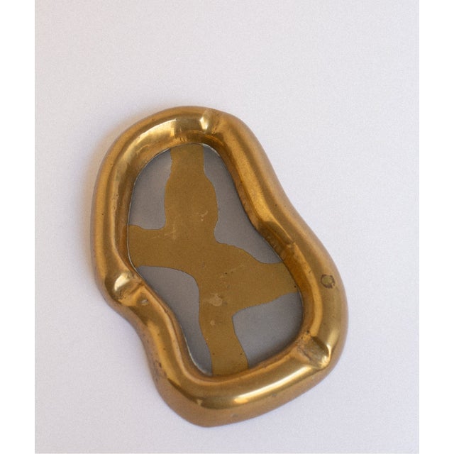 Designed by David Marshall in Spain during the 1970s, this brass vide-poche pairs an organically shaped frame with the...