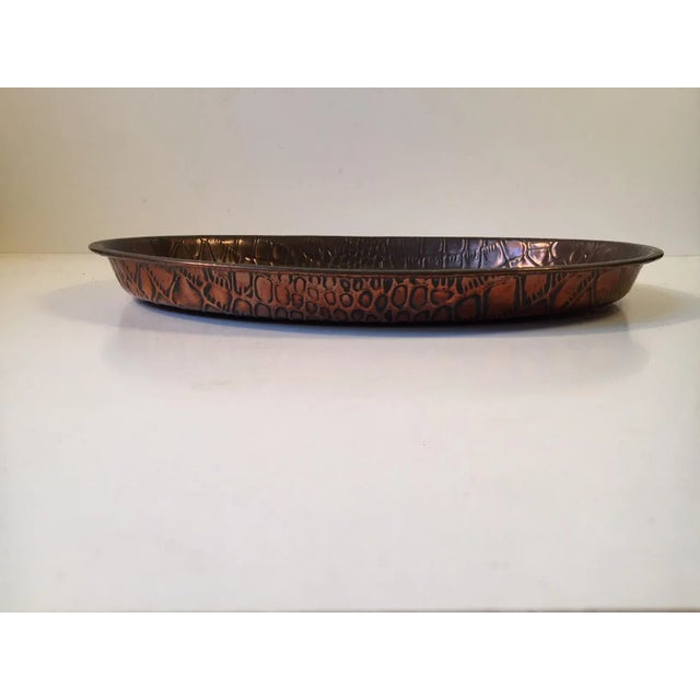 A patinated oval copper tray embossed with a Alligator skin pattern to both sides. It was Made by Joseph Sankey & Son's in...